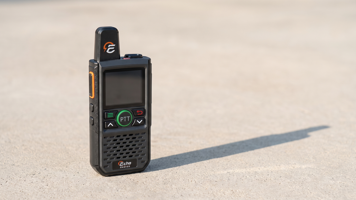 A compact Echo radio stands alone on a plain pale concrete surface in soft daylight.