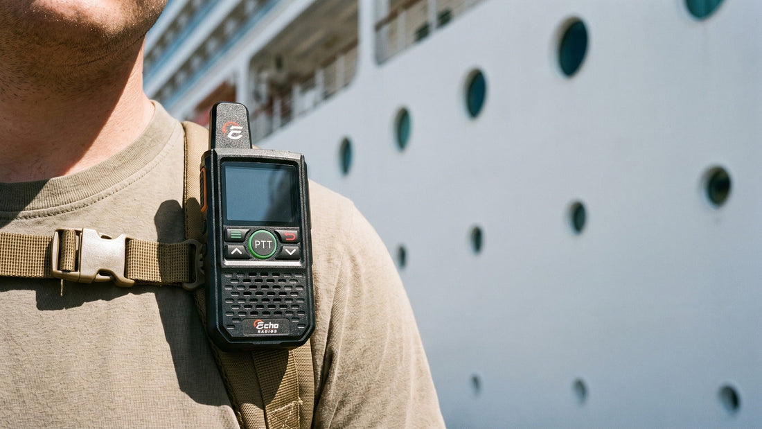 A compact handheld radio clipped to a passenger's daypack strap on a harbor quay, the white side of a cruise ship filling the background.